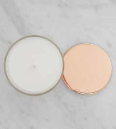 Candle with rose gold lid,  on a marble surface.
