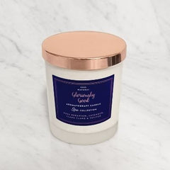 Candle with a rose gold lid and purple label on a white background