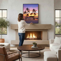 A Woman adjusting a glass wall art in a living room with a fireplace and decor.