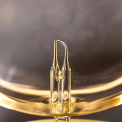 Close-up of a clear light bulb with a gold base against a dark background