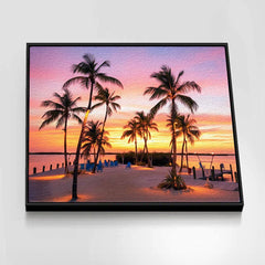 Framed artwork of a tropical sunset with palm trees and lounge chairs.